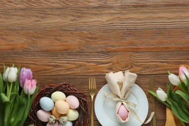 Ahşap arka planda lale çiçekleri olan Paskalya kutlaması için şık bir masa.