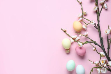 Paskalya yumurtaları ve pembe arka planda çiçek açan ağaç dallarıyla kompozisyon