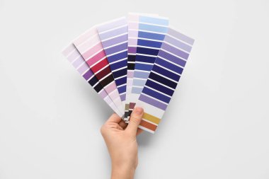 Beyaz arka planda menekşe rengi palet örnekleri olan kadın elleri. Üst görünüm