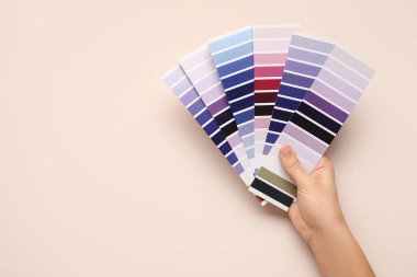 Bej arka planda menekşe rengi palet örnekleri olan kadın elleri. Üst görünüm