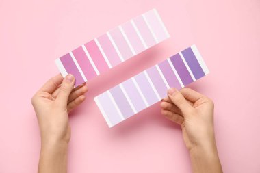Pembe arka planda mor palet örnekleri olan kadın elleri. Üst görünüm