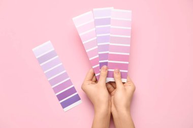 Pembe arka planda mor palet örnekleri olan kadın elleri. Üst görünüm