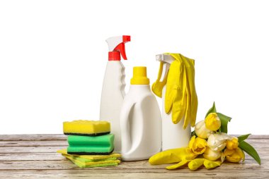 Beyaz arka planda temizlik bezleri, süngerler, lastik eldivenler ve lale çiçekleriyle dolu şişeler.