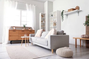 Oturma odasının içinde kanepe, masa, puf ve çekmeceler.