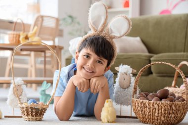 Tavşan kulaklı, sepet sepetinde çikolata yumurtaları, oturma odasında yatan civciv ve oyuncak koyunla sevimli çocuk. Paskalya kutlaması