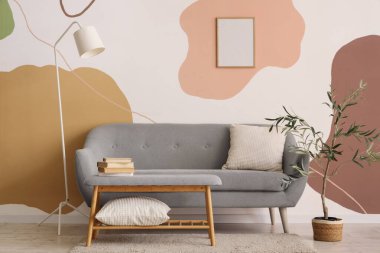 Kitapları ve şık kanepesi olan yumuşak gri bir bank.