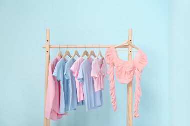 Mavi duvarın yanında kadın kıyafetleriyle dolu bir oda.