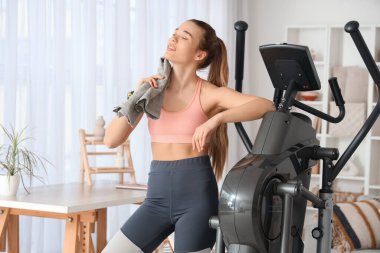 Modern egzersiz bisikletinin yanında havlusu olan genç bir bayan.