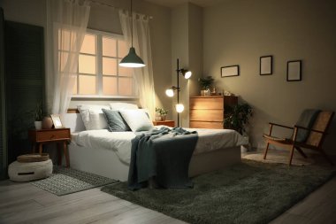 Yatak odasının içi komodinli, çekmeceli, büyük yataklı ve akşamları parlayan lambalı.