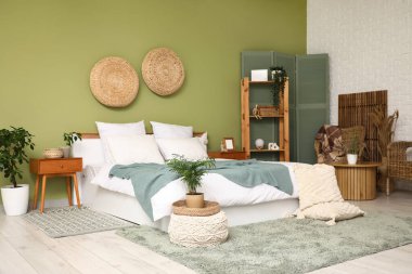 Yatak odasının içi komodinlerle, çiçeklerle, raflarla, yastıklarla ve yatakla dolu.