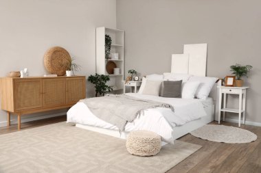 Yatağı, komodinleri ve çekmeceleri olan şık bir yatak odası.