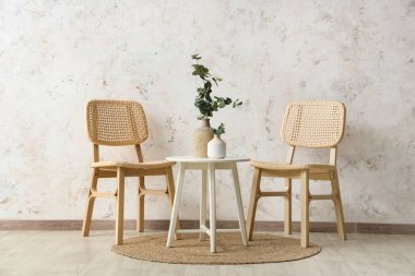 Kahve masalı rahat ahşap sandalyeler ve beyaz grunge duvarının yanında okaliptüs dalları.