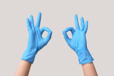 Tıbbi eldivenli kadın elleri gri arka planda iyi görünüyor.