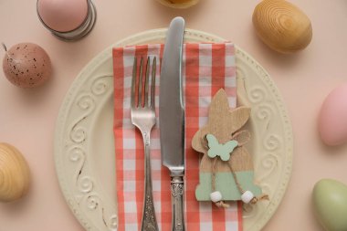 Paskalya yumurtaları ve bej arka planda ahşap tavşanla güzel bir masa.