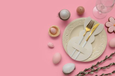 Beautiful table setting with Easter eggs, sweet cookie and pussy willow branches on pink background