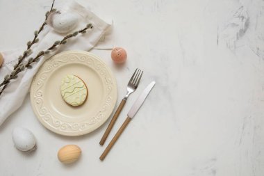 Beautiful table setting with sweet cookie, Easter eggs and pussy willow branches on white background