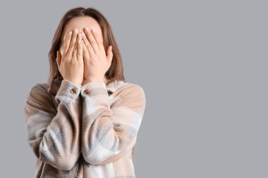 Gri arka planda panik atak geçiren genç bir kadın.