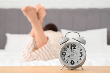Yatak odasında yatan kadına karşı alarmlı saat, yakın plan.