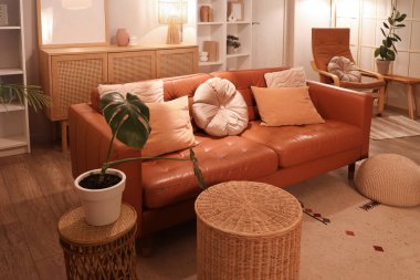 Modern oturma odasının içinde kahverengi kanepe, çekmeceler ve gece parlayan lamba.