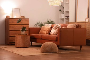 Modern oturma odasının içinde kahverengi kanepe, çekmeceler ve akşam lambaları var.