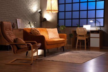 Akşamları kırmızı koltuğu, koltuğu, işyeri ve parlak lambaları olan modern oturma odasının içinde.