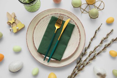 Beautiful table setting with Easter eggs, wooden bunny and pussy willow branches on grey background