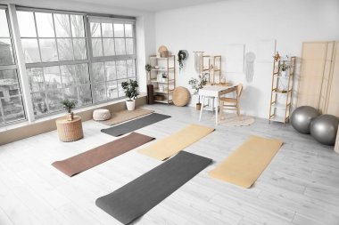 Masası, raf ünitesi ve paspasları olan yoga stüdyosunun içi.