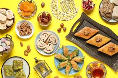 Sarı zemin üzerinde geleneksel Ramazan tatlıları, tasbih ve hilal