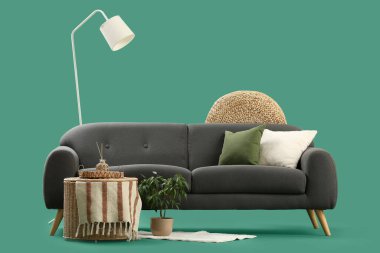 Şık gri kanepe, sehpa ve yeşil arka planda standart lamba.