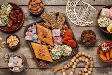 Farklı doğu yemekleri, tasbih ve ahşap arka planda dekoratif hilal içeren kompozisyon. Ramazan kutlaması