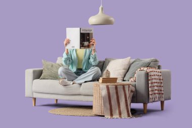 Mor arka planda gri koltukta dergi okuyan genç bir kadın.