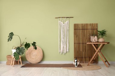 Yoga stüdyosunun içinde minder, bitki ve masa var.