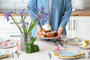 Paskalya kutlaması için mutfak masasına paskalya pastalarıyla tabak koyan bir kadın. Yakın çekim.