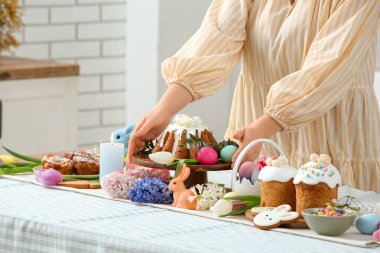 Bayanların elleri paskalya sofrasını boyalı yumurta ve paskalya pastasıyla süslüyor. Yakın çekim.