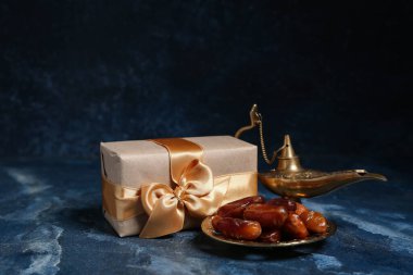 Aladdin lambası, tarihler ve hediye kutusu mavi grunge arka planda. Ramazan kutlaması