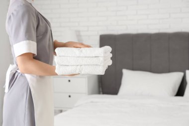 Otel odasında temiz havluları olan genç oda hizmetçisi.