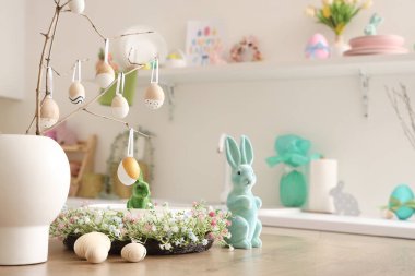 Mutfak masasında ağaç dalları, yumurtalar, Paskalya tavşanları ve çelenkler olan vazo, yakın plan.