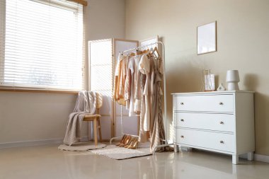 Elbise askılığı, sandalye ve katlama ekranlı butiğin içi.