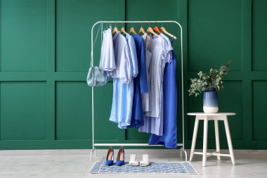 Ayakkabılı elbise askısı ve butikte yeşil duvarın yanındaki masa.