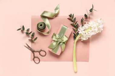Çiçekli hediye kutusu, bej arka planda ambalaj kağıdı ve makas. Uluslararası Kadınlar Günü