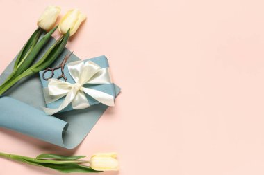 Laleli hediye kutusu, bej arka planda ambalaj kağıdı ve makas. Uluslararası Kadınlar Günü