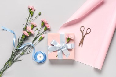 Karanfilli hediye kutusu, beyaz arka planda ambalaj kağıdı ve makas. Uluslararası Kadınlar Günü
