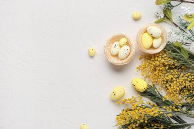 Yuvaları, çiçekleri ve beyaz grunge arka planında Paskalya yumurtaları olan kompozisyon