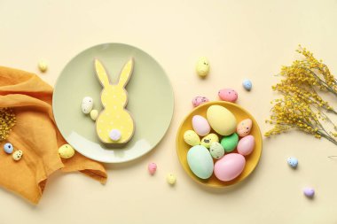 Tabaklarla, çiçeklerle ve bej arka planda Paskalya yumurtalarıyla kompozisyon