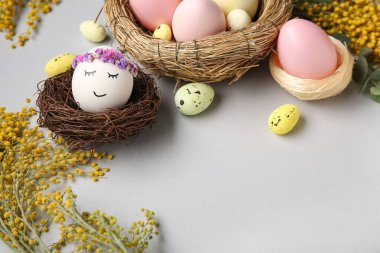 Yuvaları, çiçekleri ve gri arka planda Paskalya yumurtaları olan kompozisyon, yakın plan