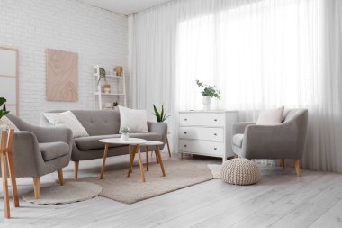 Perdeleri, koltukları ve koltukları olan aydınlık oturma odasının içinde.