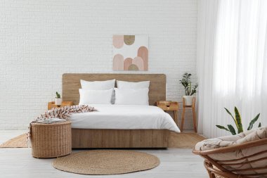 Perdeleri, masaları ve resimleriyle aydınlık yatak odasının içinde.