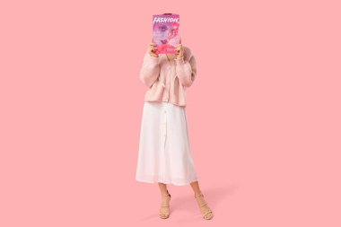 Pembe arka planda dergisi olan genç ve güzel bir kadın.