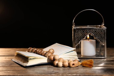 Dua boncuklu Kuran, Müslüman lambası ve siyah arka planda yanan bir mum. Ramazan kutlaması
