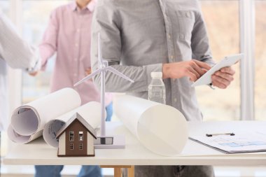 Ev modelli rüzgâr türbini ve ofiste çalışan mühendislere karşı planlar.